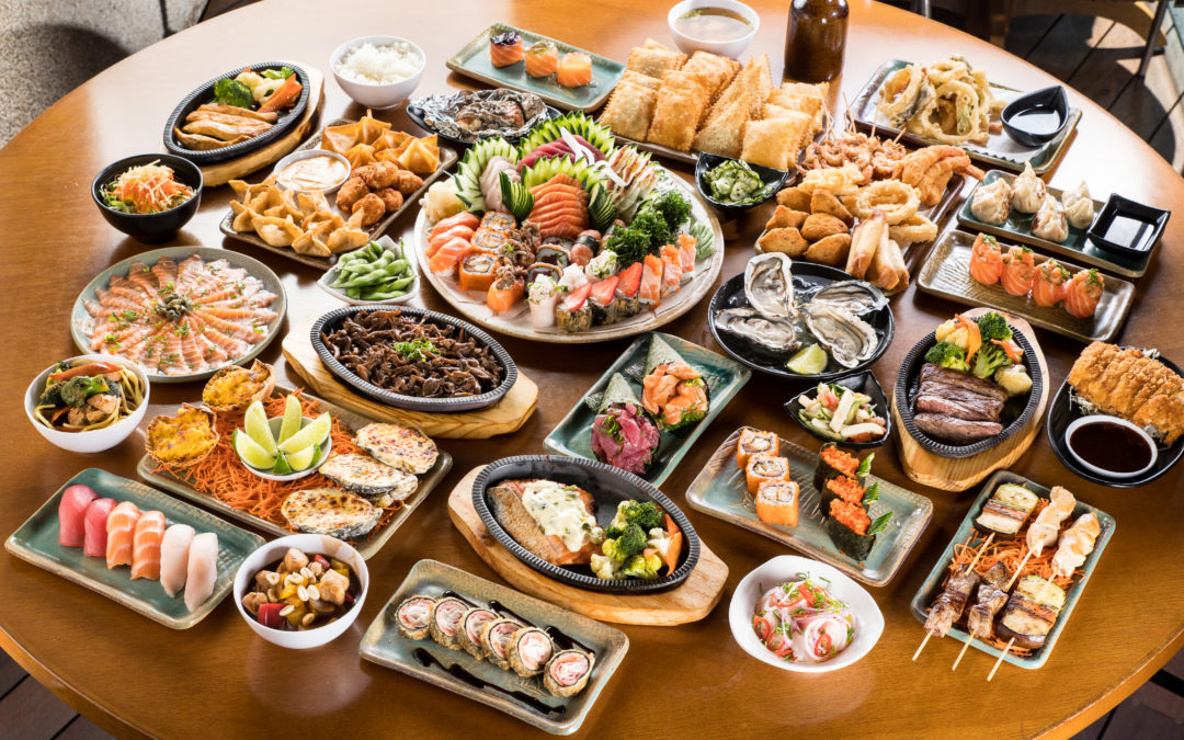 mesa de madeira repleta de pratos com diferentes comidas japonesas